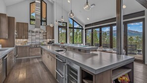 A modern kitchen with large windows, a central island, and a view of the outdoors. - Hot Tub + Ski Shuttle | Vickery's Vantage (Breckenridge)
