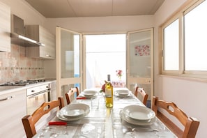 A dining area with a table set for six, a wine bottle, and a view of the outdoors.