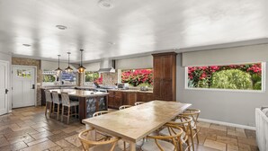 Une cuisine spacieuse avec un îlot central, des chaises en bois et une grande table à manger.