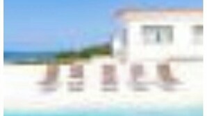A beachfront property with a white building, a sandy beach, and a clear blue sky. - Luxury Beach Villa - Amoreira (Casal da Lagoa Seca)