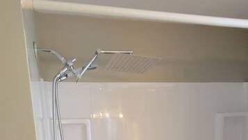 A bathtub with a showerhead and faucet, a window, and a door.