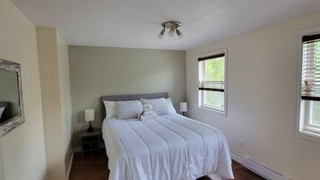 A bedroom with a large bed, a nightstand, a lamp, and a ceiling light fixture.