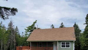 A single-story house with a front porch, a small attached garage, and a well-maintained lawn. - Naini's Rental, 4 bedrooms, located on Deer Island, N.B. 5 mins from the water. (Lords Cove)