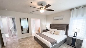A spacious bedroom with a large bed, a ceiling fan, a nightstand, and a window with curtains. - Beautiful Beach Longboat Key Townhouse (Longboat Key)