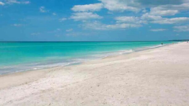 A beach with clear turquoise water and a wide sandy shore under a partly cloudy sky. - Beautiful Beach Longboat Key Townhouse (Longboat Key)