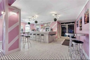 A bar area with a bar counter, stools, and a patterned floor. - 3 bedroom villa (Sleeps 8) in a tropical Tuscan style resort near Disney (Davenport)