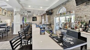 A bar area with a long counter, stools, and a variety of bottles. - 3 bedroom villa (Sleeps 8) in a tropical Tuscan style resort near Disney (Davenport)