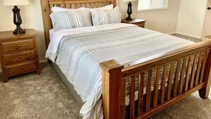 A bedroom with a wooden bed, two nightstands, a window with blinds, and a carpeted floor. - Close to Glacier Park, Flathead Lake, Whitefish Mountain Resort (Kalispell)