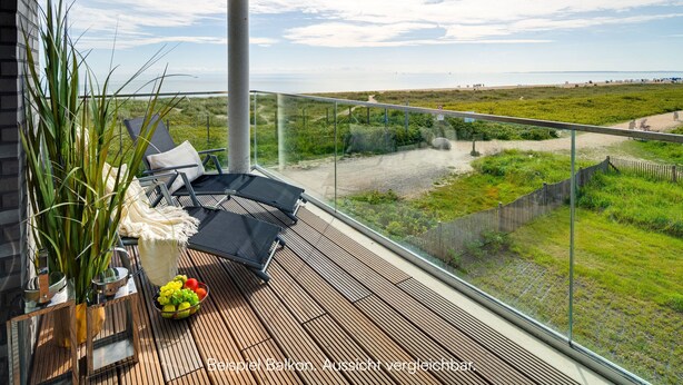A balcony with a view of the beach, a glass railing, and a table with fruits and a vase of plants. - "BeachLoungeThree" vacation apartment on the beach with sun terrace, sauna & sea view (Olpenitz)
