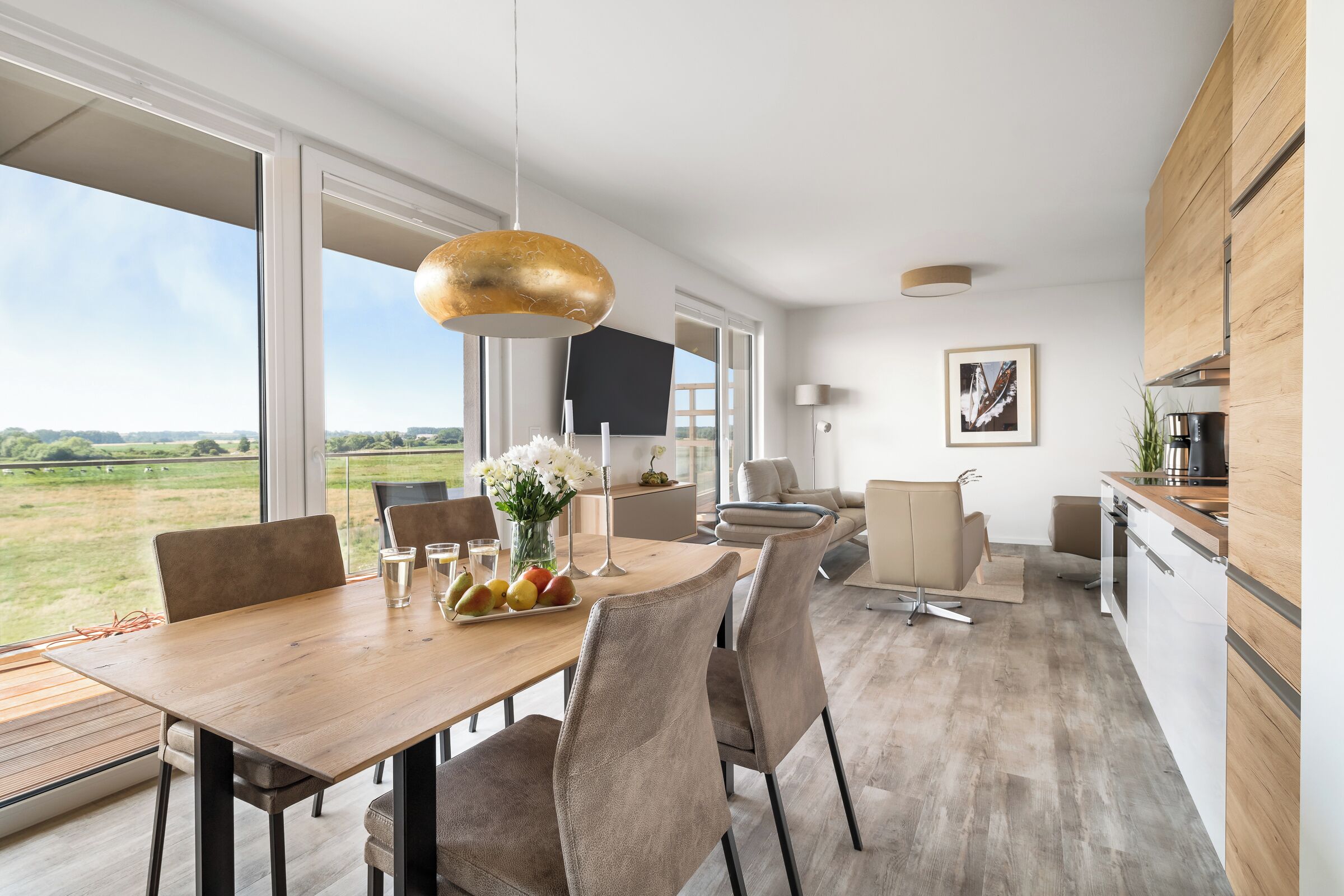 A modern kitchen with a wooden countertop, a large window, and a dining area with a wooden table and chairs.