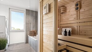 Een moderne badkamer met een houten sauna, een groot raam en een ingebouwde wasmachine.