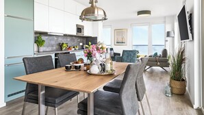 Een moderne keuken met een houten eettafel, grijze stoelen en een hanglamp.