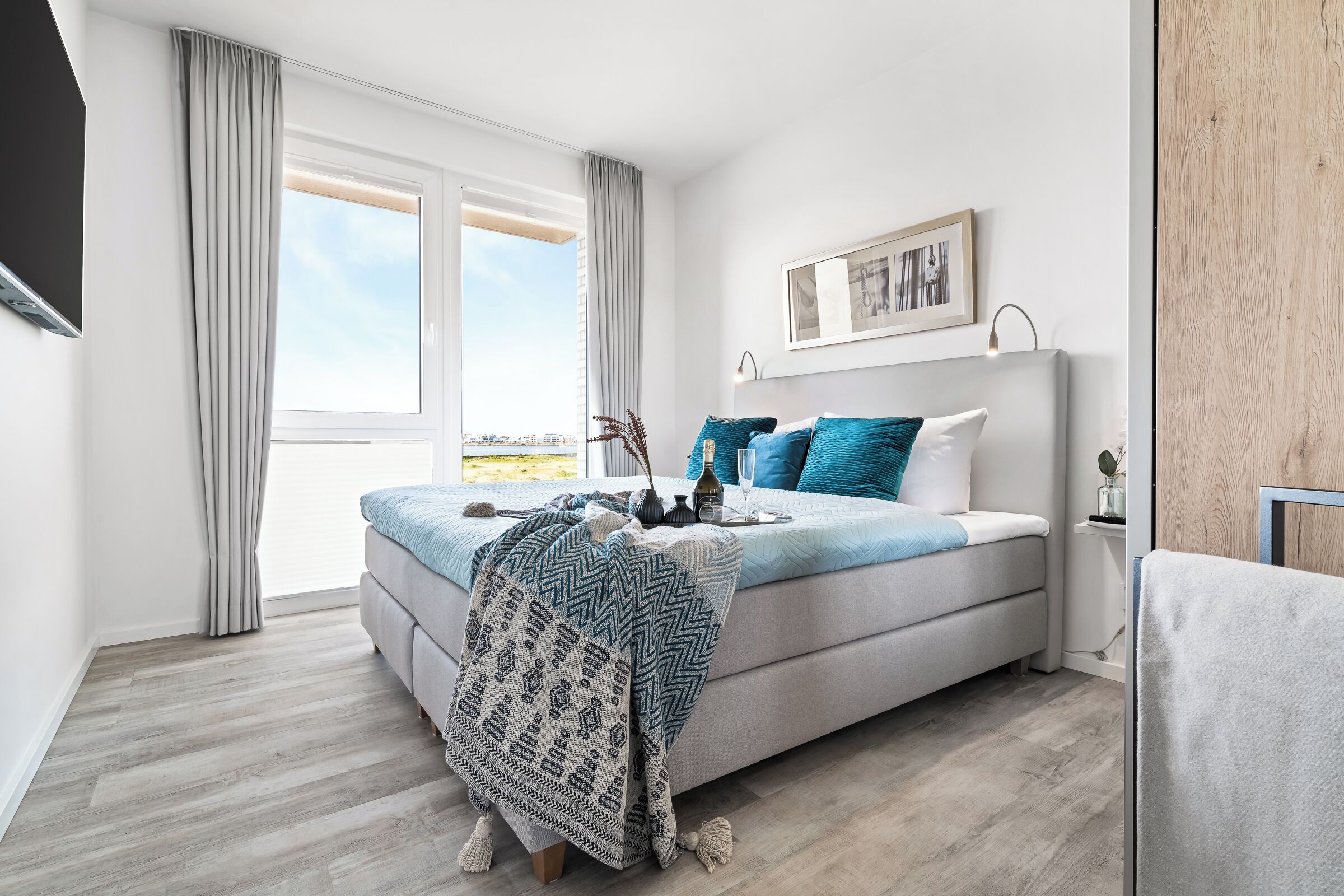 A modern bedroom with a large bed, a view of the city, and a wooden wall.