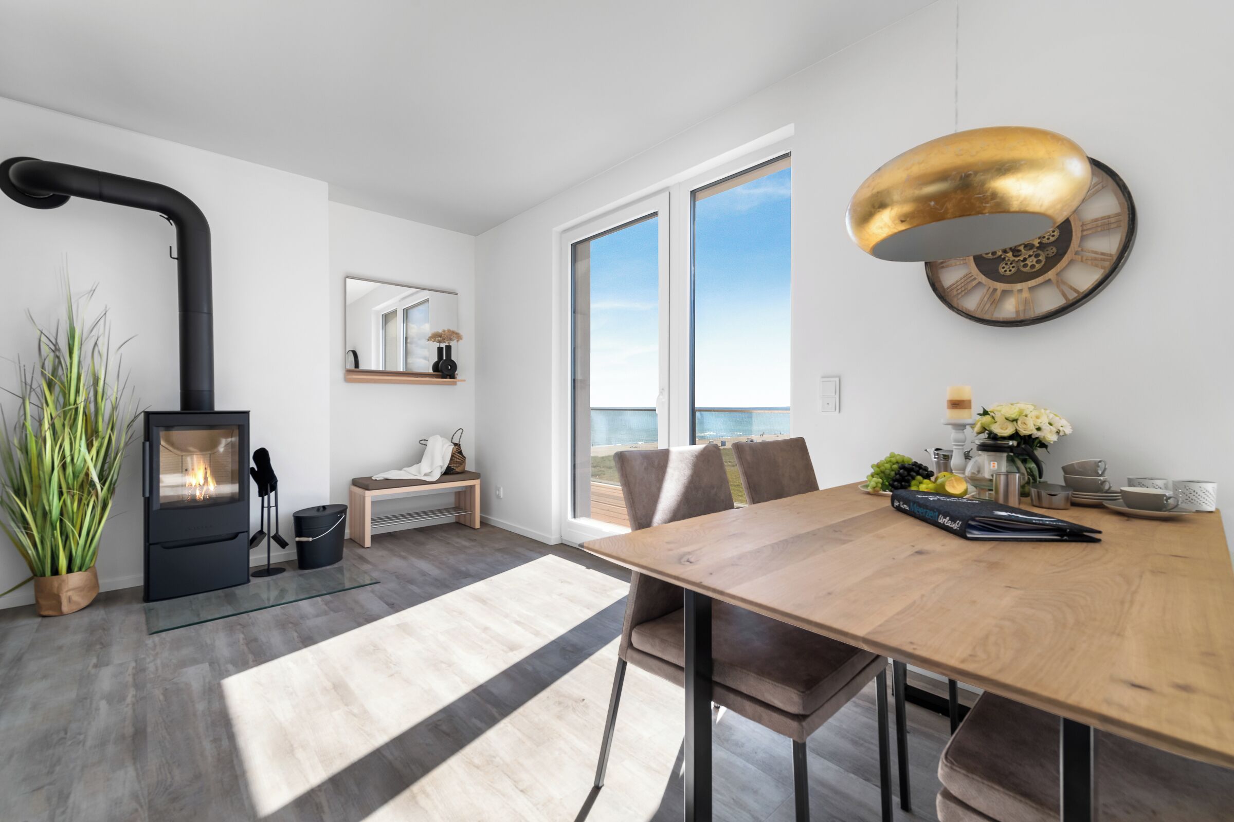 A modern living room with a fireplace, a dining table, and a large window offering a view.