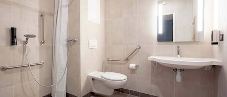 A modern bathroom with a shower, toilet, and sink, equipped with grab bars and a mirror.