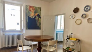 A dining area with a round table, four chairs, a painting on the wall, and a collection of plates on the wall. - Pinzochere - Two Bedroom Apartment, Sleeps 4 (Firenze)