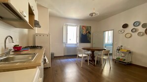 A modern kitchen with a wooden countertop, a sink, and a stove. There is a dining area with a table and chairs. - Pinzochere - Two Bedroom Apartment, Sleeps 4 (Firenze)