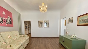 A spacious room with a floral sofa, a green cabinet, and artwork on the walls. - Pinzochere - Two Bedroom Apartment, Sleeps 4 (Firenze)