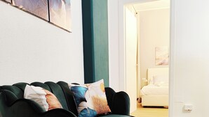 A green sofa with multiple cushions in a room with wooden flooring and a white wall. - Regina House in the center of Cagliari (Cagliari)