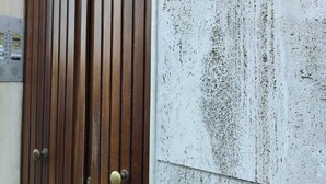 A wooden double door with a plaque reading "Regina House Holiday Home" on a textured wall. - Regina House in the center of Cagliari (Cagliari)