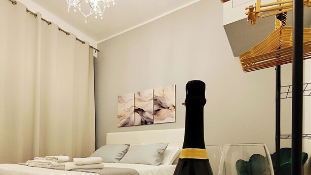 A hotel room with a bed, a bottle of Müller Thurgau Durello wine, and a glass of wine on a table. - Regina House in the center of Cagliari (Cagliari)