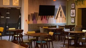 A restaurant with wooden tables and chairs, hanging pendant lights, and a wall-mounted television. - Lodge - Sleeps 8 - Parking, Wifi, (Clacton-on-Sea)