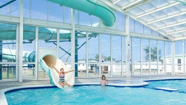 An indoor water park with a large pool, a water slide, and a glass-enclosed structure. - Lodge - Sleeps 8 - Parking, Wifi, (Clacton-on-Sea)