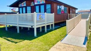 A small, wooden building with a sign that reads "Pottery Shop." It has a white fence in front and a ramp leading to the entrance. - Lodge - Sleeps 8 - Parking, Wifi, (Clacton-on-Sea)