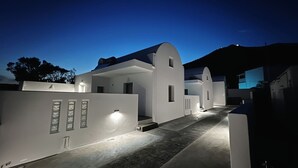 Ein modernes Gebäude mit weißer Fassade und gewölbtem Dach, mit einem zentralen Eingang, Stufen und beleuchteten Wänden.