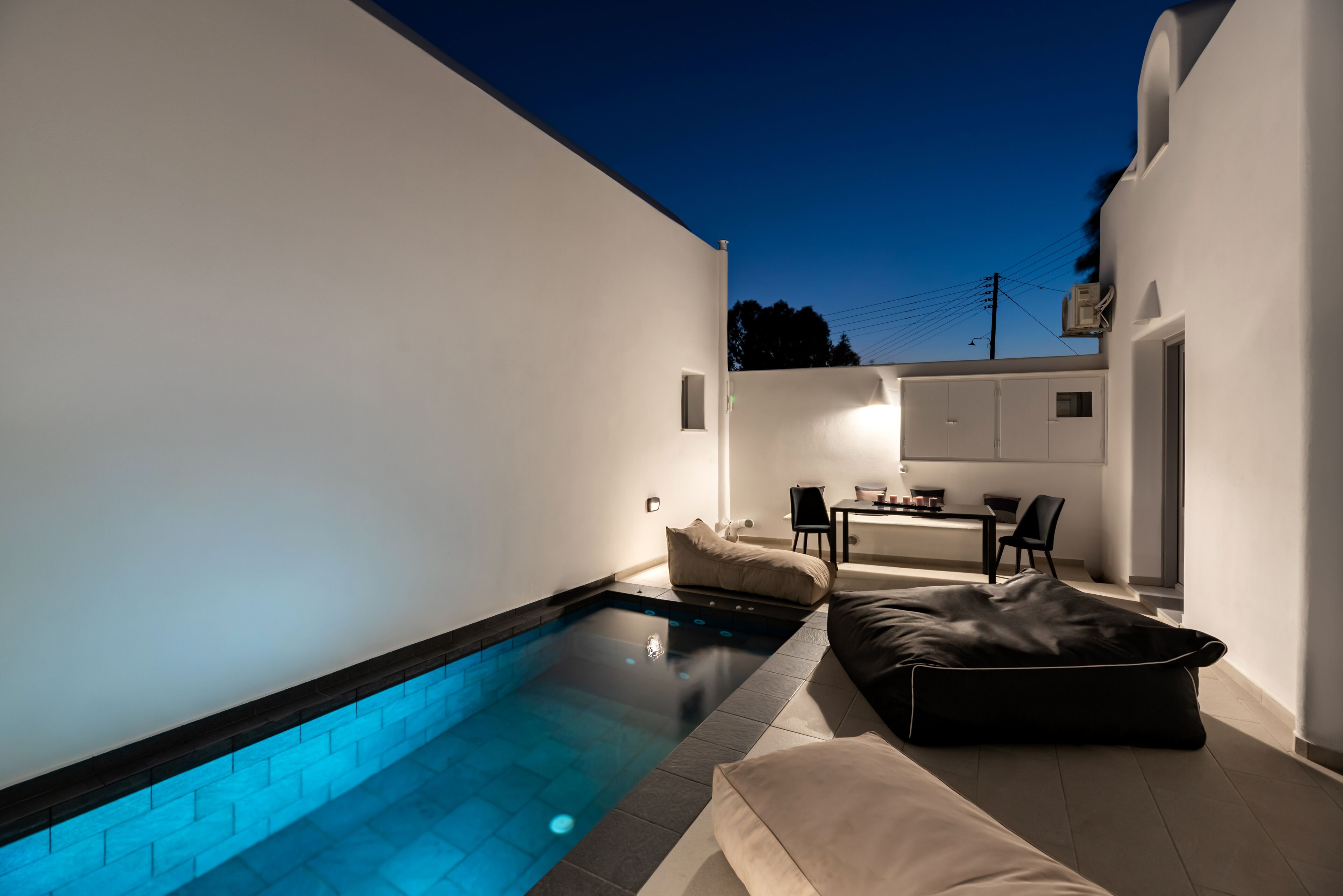 A modern outdoor pool area with a built-in seating area and a small table.