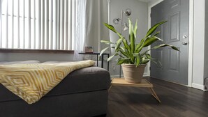 A modern bedroom with a grey sofa, a potted plant, and a bedside table. - Serene 2BR: Near-Town Convenience Meets Nature Getaway, Ideal for All Travelers (Nashport)