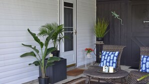 A porch with a door, potted plants, wicker chairs with patterned cushions, and a small table with candles. - Serene 2BR: Near-Town Convenience Meets Nature Getaway, Ideal for All Travelers (Nashport)