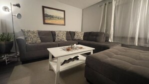 A living room with a sofa, a coffee table, a lamp, and a painting on the wall. - Serene 2BR: Near-Town Convenience Meets Nature Getaway, Ideal for All Travelers (Nashport)