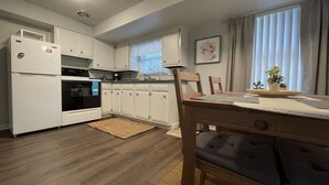 A compact kitchen with white cabinets, a built-in oven, and a dining area with a wooden table and chairs. - Serene 2BR: Near-Town Convenience Meets Nature Getaway, Ideal for All Travelers (Nashport)