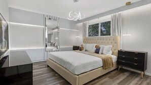 Une chambre moderne avec un grand lit, une commode, un miroir et un téléviseur.