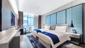 Quarto de hotel moderno com uma cama grande, uma escrivaninha, uma cadeira e uma televisão.