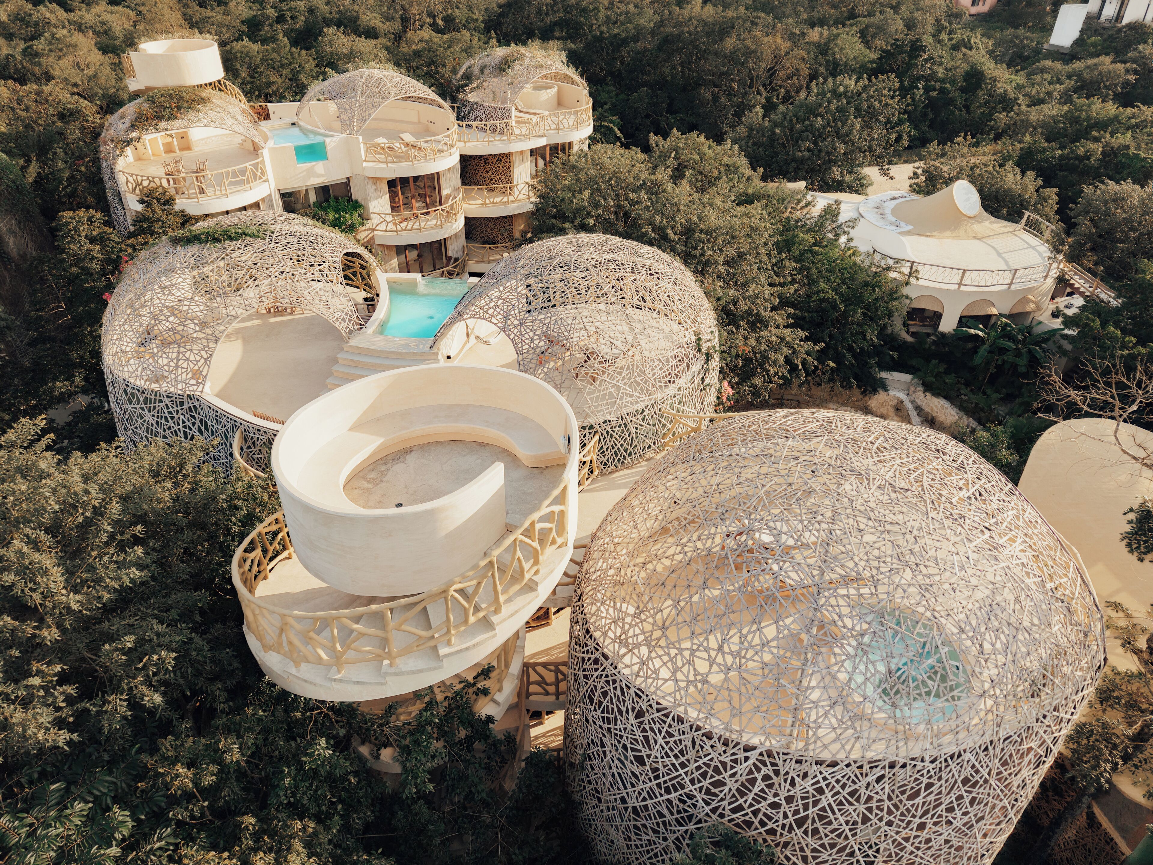 A resort with multiple dome-shaped buildings, each with a circular seating area and a pool.