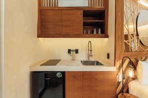Una cocina compacta con armarios de madera, un lavamanos de acero inoxidable y un lavavajillas.