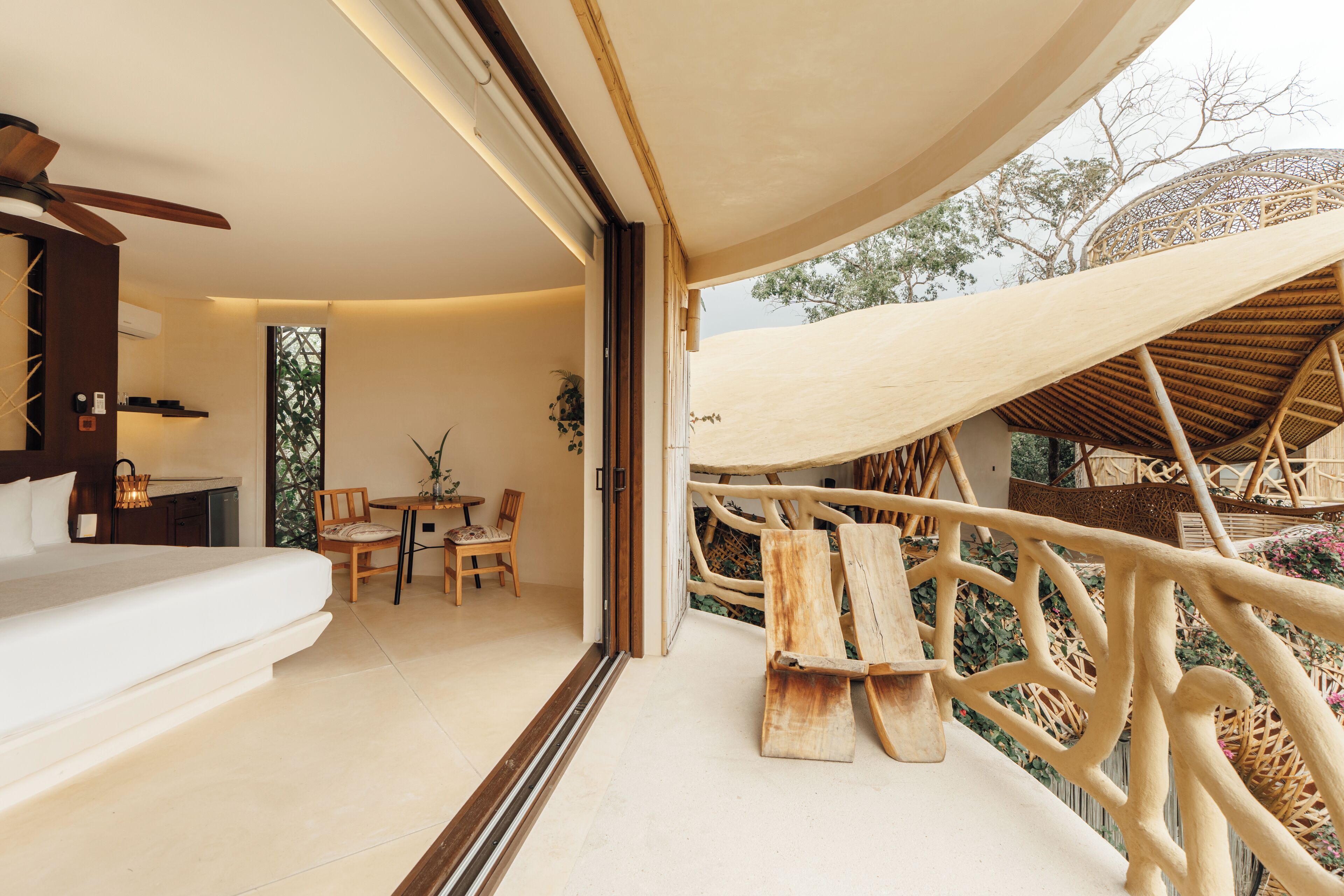 Un interior moderno con una cama, un área de comedor y un balcón con barandillas de madera.