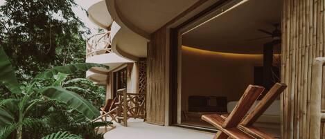 A poolside area with a curved deck, wooden lounge chairs, and lush greenery.