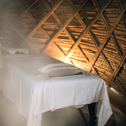 A bed in a room with a geometric wooden ceiling design.
