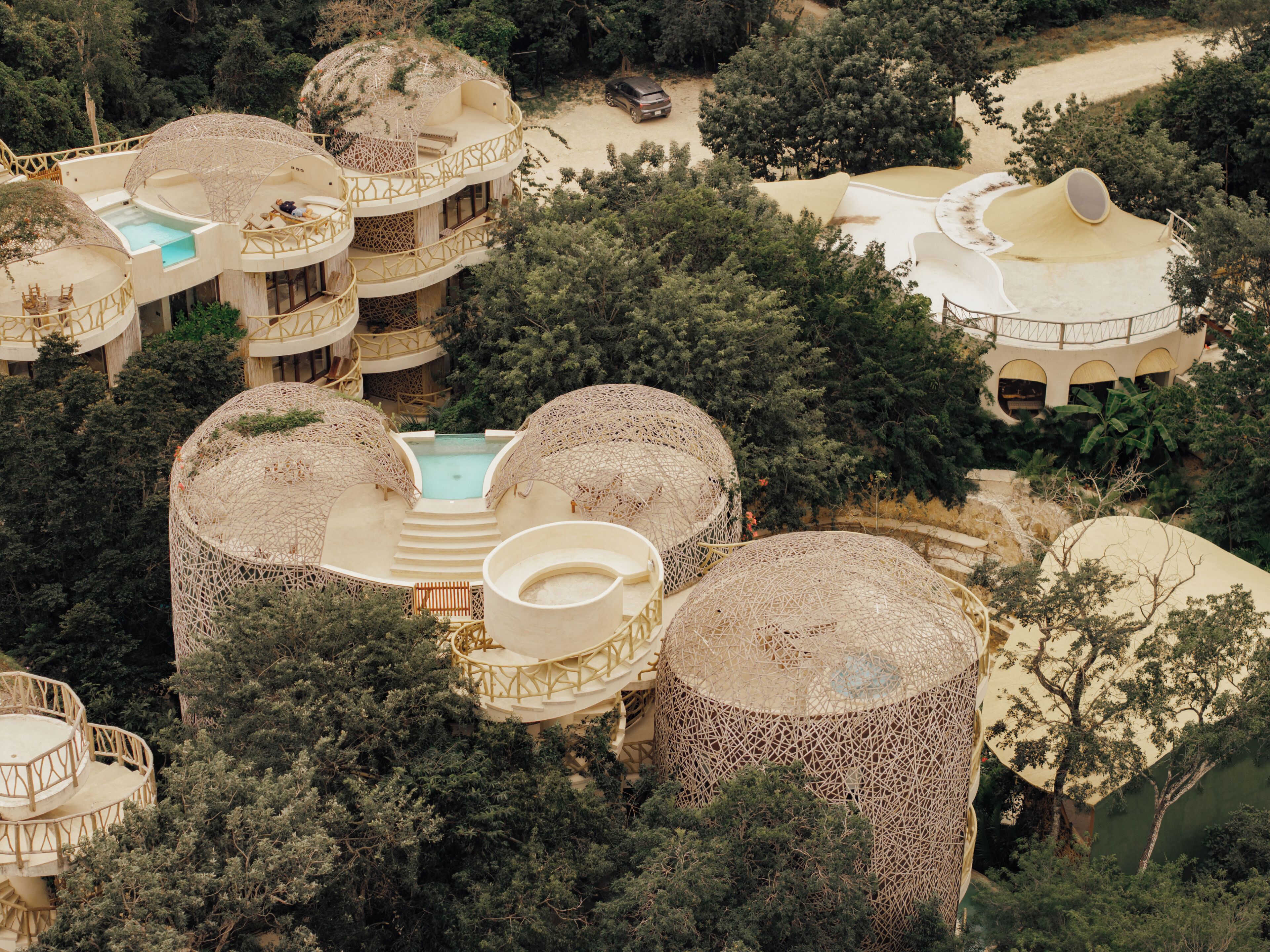 Un complejo turístico con varias construcciones en forma de cúpula, una piscina central y exuberante vegetación circundante.