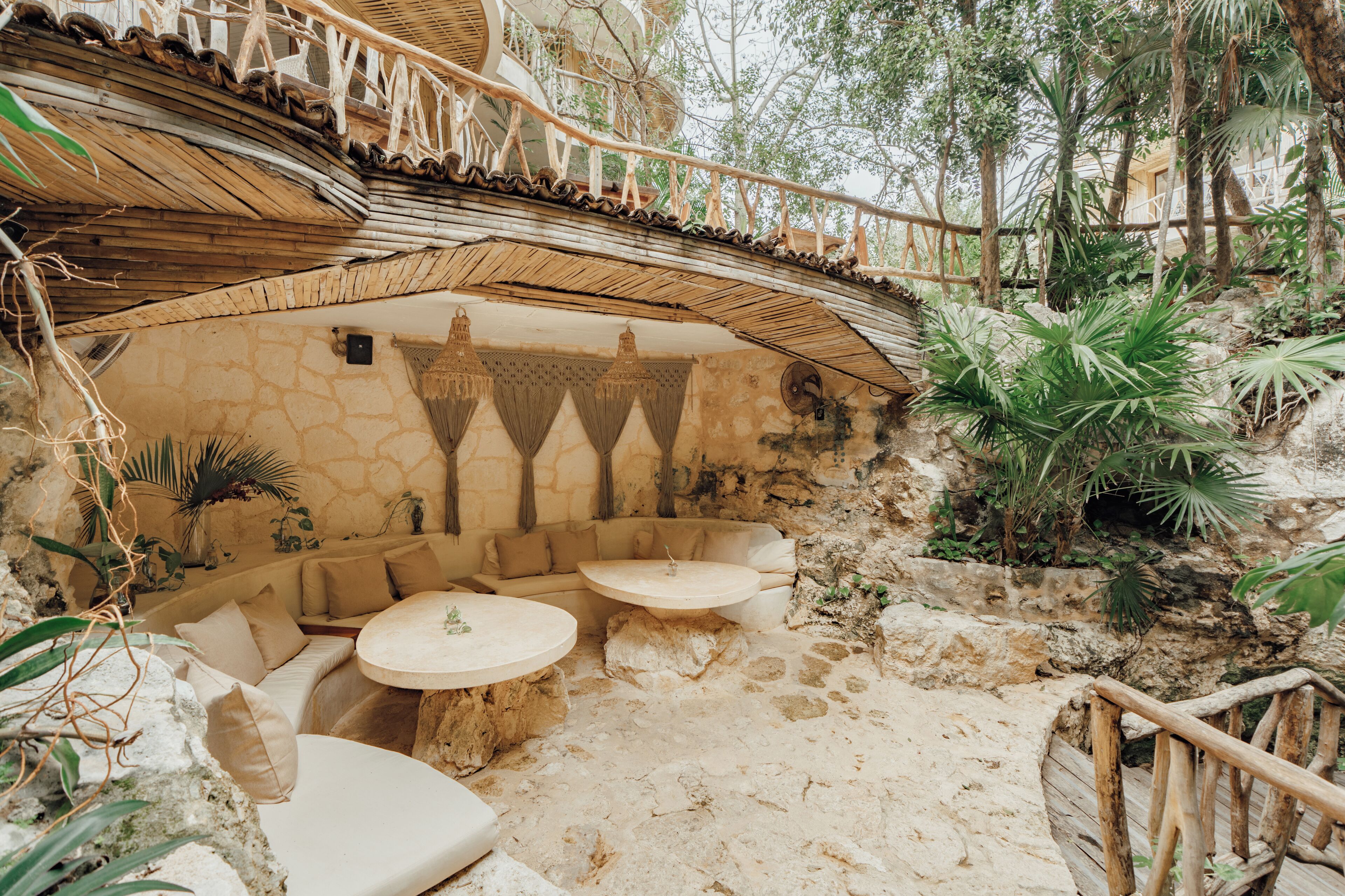An outdoor seating area with stone walls, a wooden deck, and tropical plants.