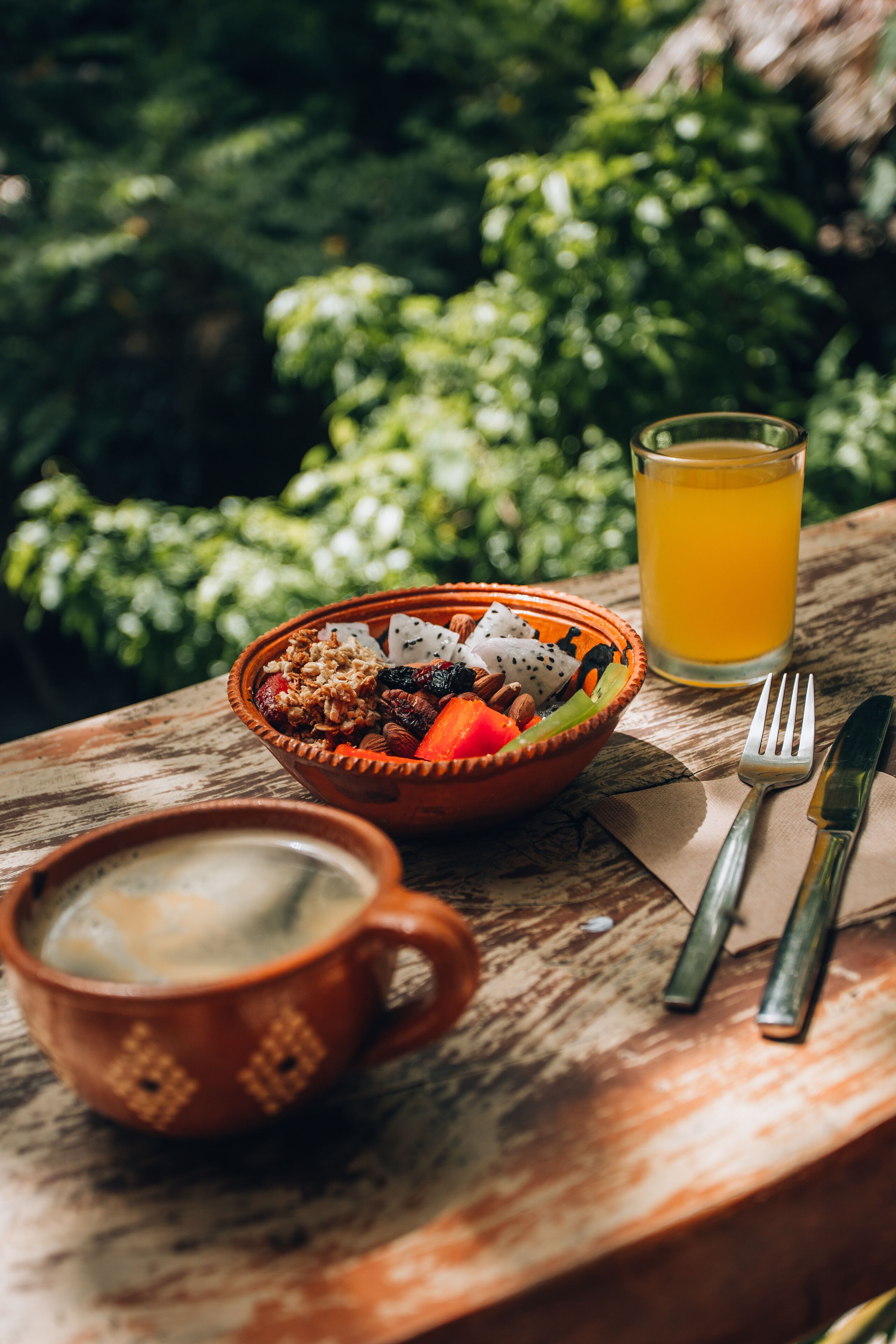 A meal with a bowl of food and a glass of orange juice on a wooden table.