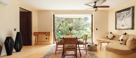 A spacious living area with a round table and chairs, a sofa, and a ceiling fan.