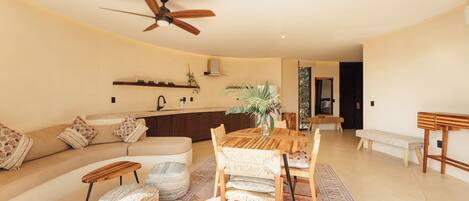 Un vaste espace de vie comprenant une table à manger en bois, un canapé et un ventilateur de plafond.