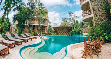 Una piscina al aire libre, sombrillas, sillones reclinables de piscina