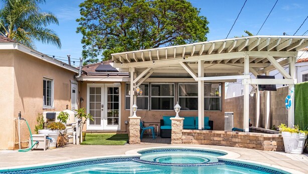 A backyard with a swimming pool, outdoor seating, and a covered patio area. - Perfect Oasis w/ Pool, jacuzzi, close to airports, beach, entertainment & more! (Long Beach)
