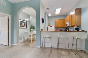 Enjoy meals in this kitchen with a dining area, featuring a refrigerator, microwave, and bar stools.