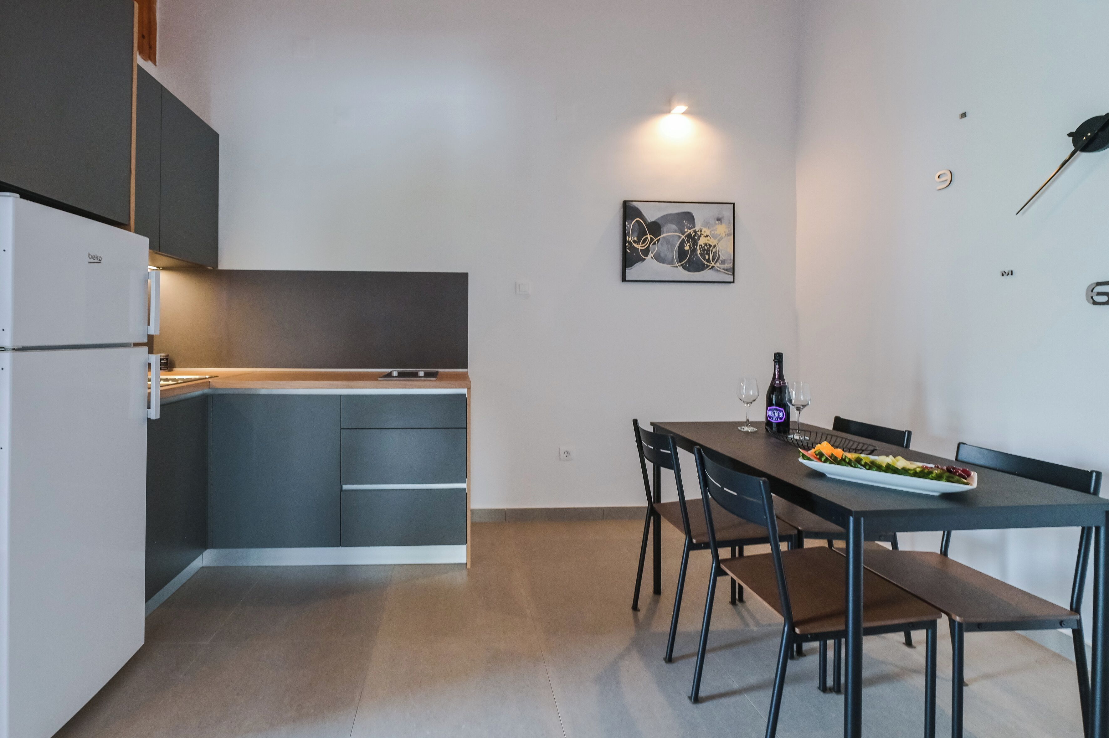 Une cuisine compacte avec des meubles gris et un coin repas avec une table dressée pour deux personnes.